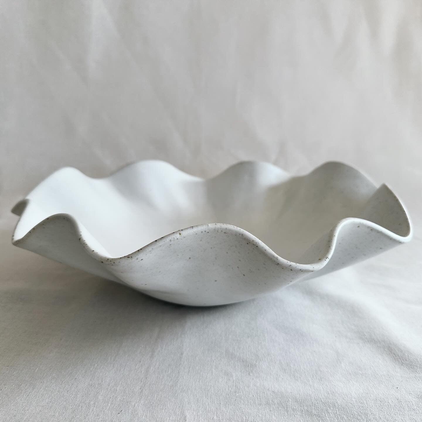 Side view of a wavy speckled white bowl