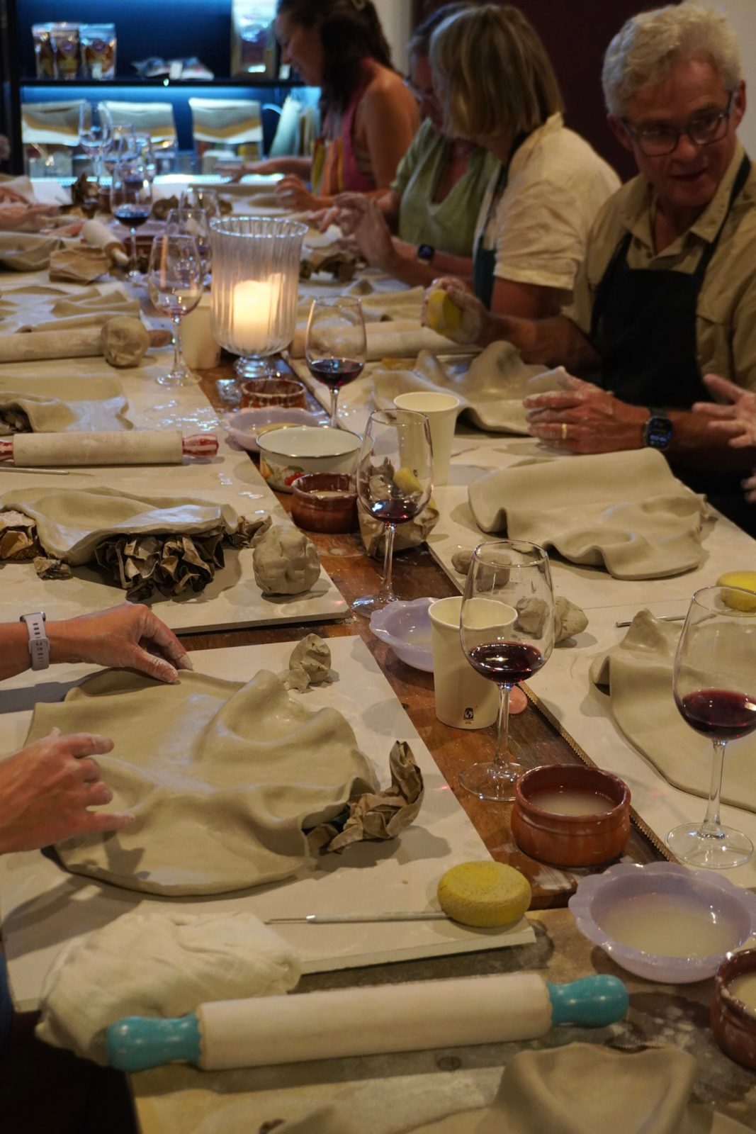 Guests shaping clay by candlelight