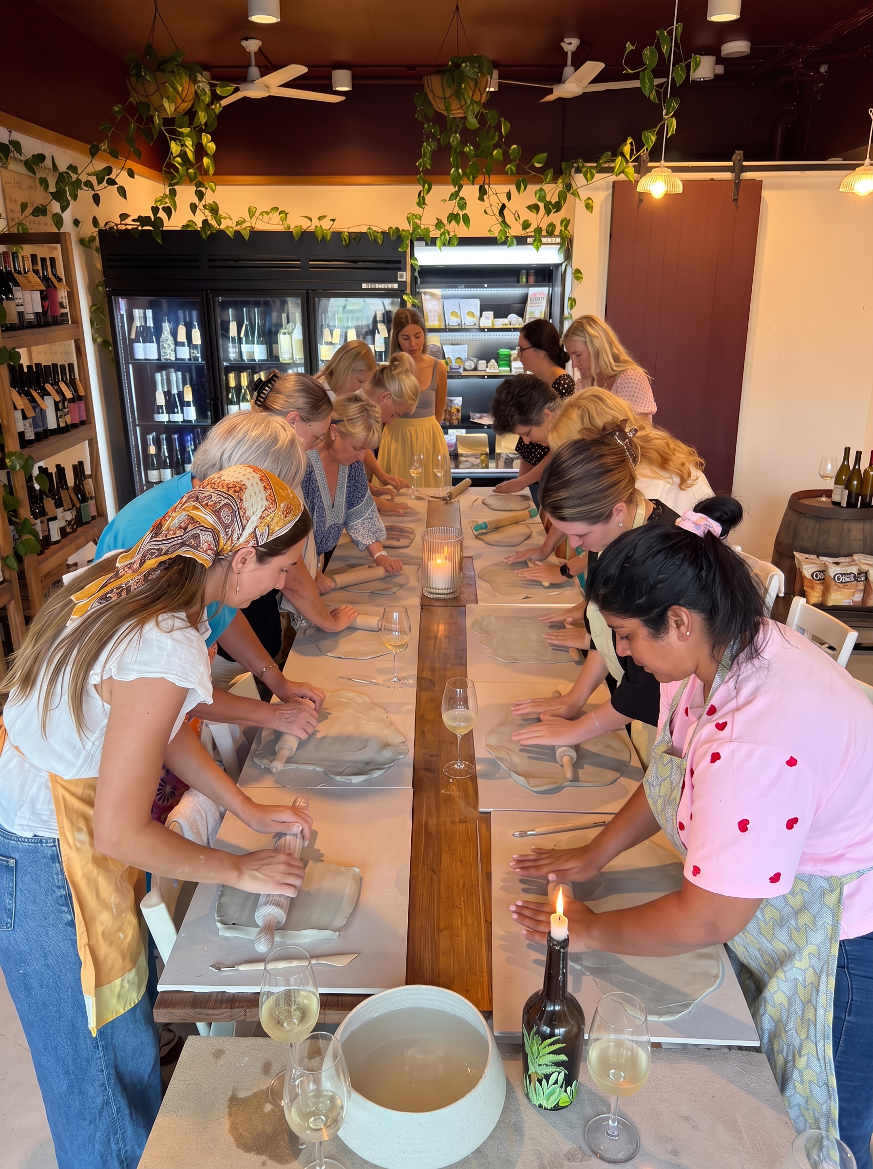 Friends making ceramics together at a long table with wine
